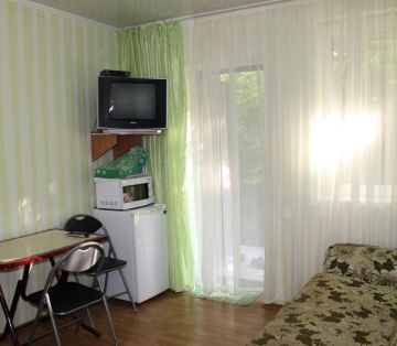Телевизор и обеденная зона в номере Комфорт отель Прибой Саки