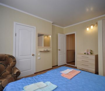 Комод с цветочной композицией, кровать, кресло в номере «Лагуна» отель Прибой Саки