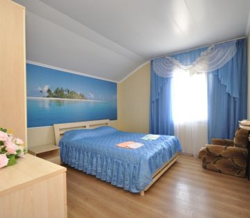 Двуспальная кровать, кресло, фотообои с красивым морским видом в номере «Лагуна» отель Прибой Саки