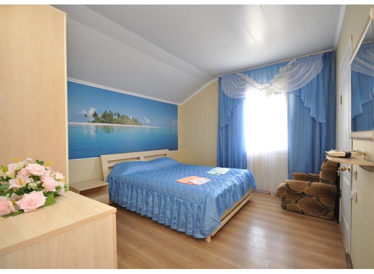 Двуспальная кровать, кресло, фотообои с красивым морским видом в номере «Лагуна» отель Прибой Саки