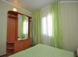 Шкаф, кровать с зеленым покрывалом и занавесками в тон в номере «Ривьера» отель Прибой Саки