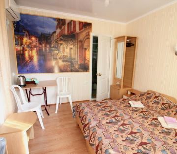 Два спальных места, обеденная зона с чайником у стены с ночным городом  в номере Стандарт 2х местный отель Прибой Саки