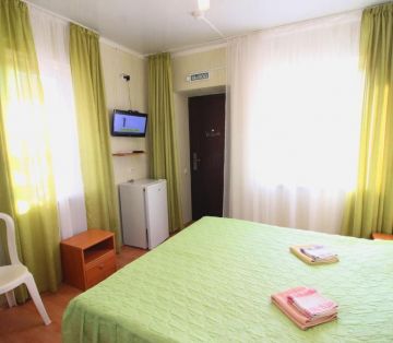 Кровать с зеленым покрывалом и занавесками в тон в номере Стандарт 2х местный отель Прибой Саки