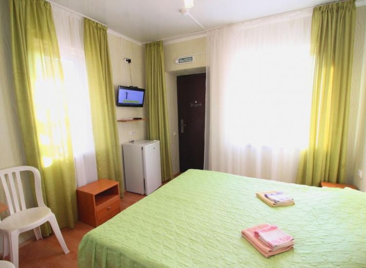 Кровать с зеленым покрывалом и занавесками в тон в номере Стандарт 2х местный отель Прибой Саки