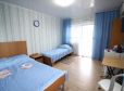 Спальные места с синим покрывалом и занавески в тон в номере Стандарт 3х местный отель Прибой Саки