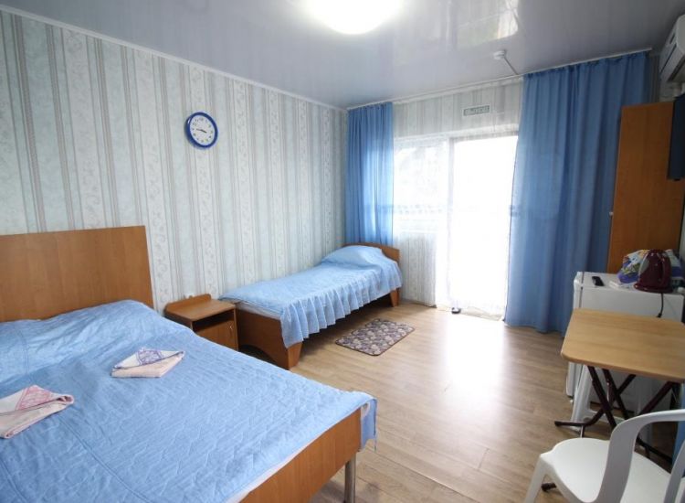 Спальные места с синим покрывалом и занавески в тон в номере Стандарт 3х местный отель Прибой Саки