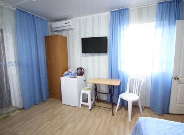 Обеденная зона, шкаф, телевизор, синие занавески в номере Стандарт 3х местный отель Прибой Саки
