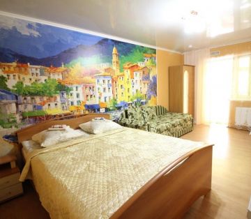 Двуспальная кровать в окружении теплых желтых стен с фотообоями города в номере Стандарт 4х местный отель Прибой Саки